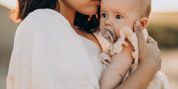 Mother holding a baby with a pacifier – Macy's Cradle pregnancy resource center in Sapulpa, Oklahoma